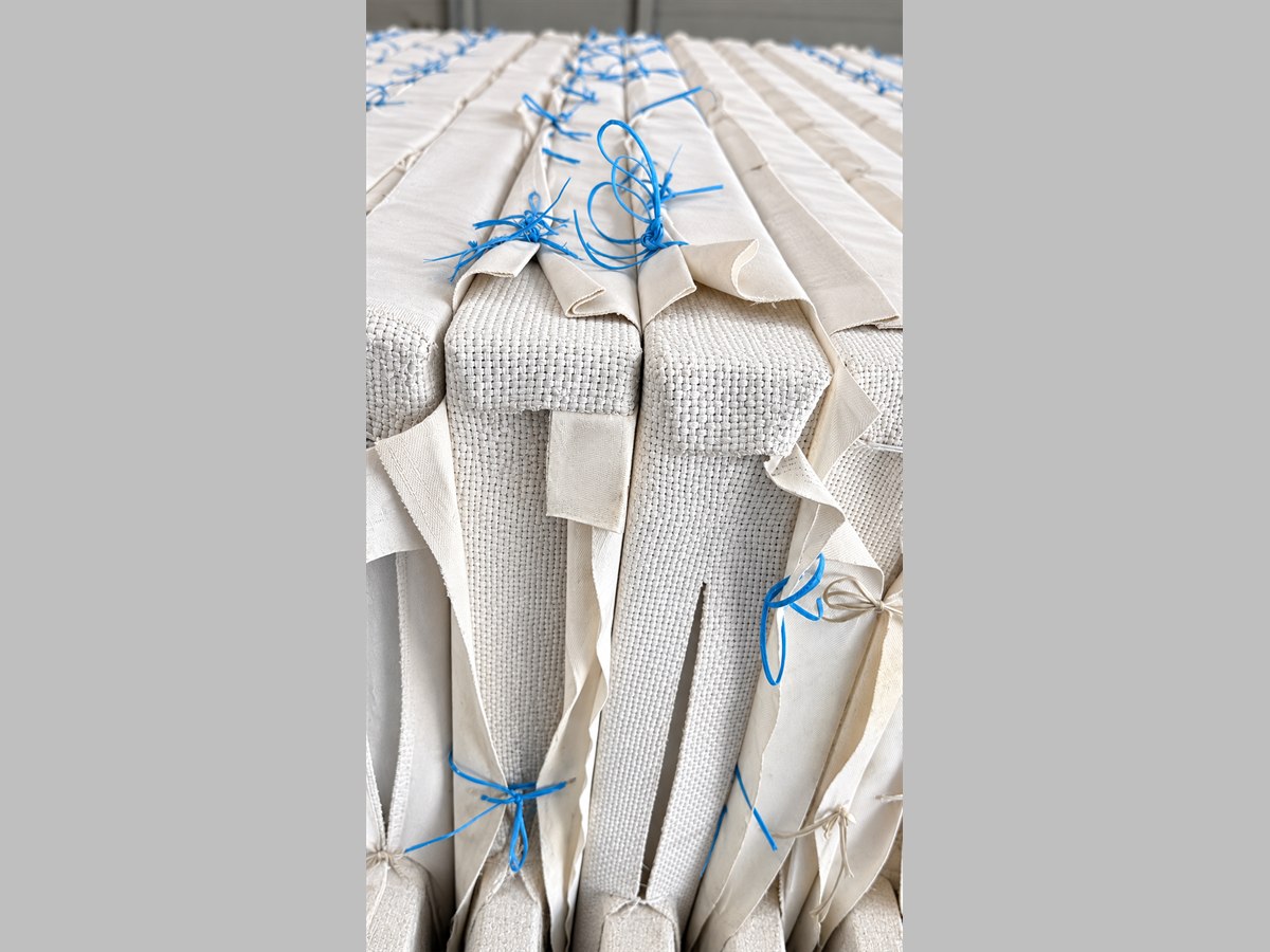 Filter press cloths dressed over plates at DFR, the coarse woven backer cloth visible beneath the smoother filter cloth, each pair tied off